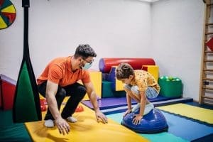 A therapist guiding a young child through a balance exercise, promoting physical and cognitive development.