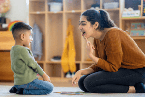 Compassionate ABA therapist engaging with attentive young boy in an educational game during a therapy session.